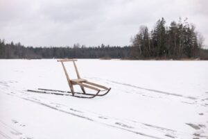 Traditionell träkälke av björk på en snötäckt, frusen sjö
