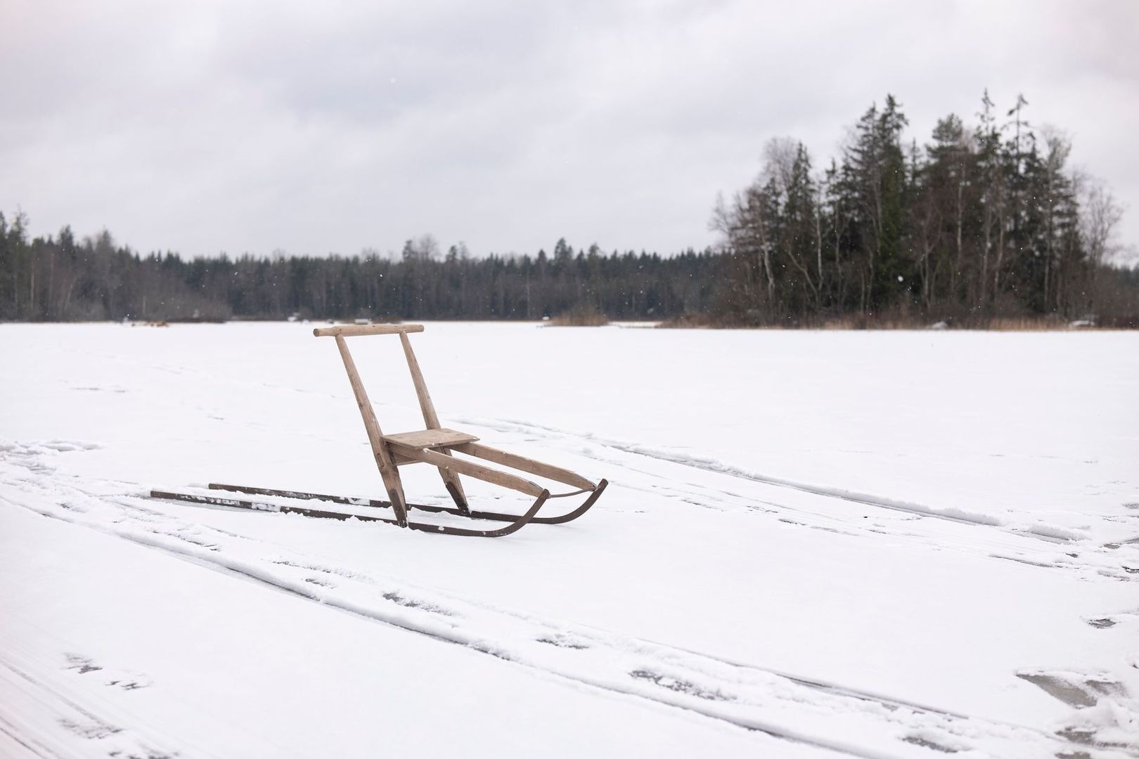 Traditionell träkälke av björk på en snötäckt, frusen sjö